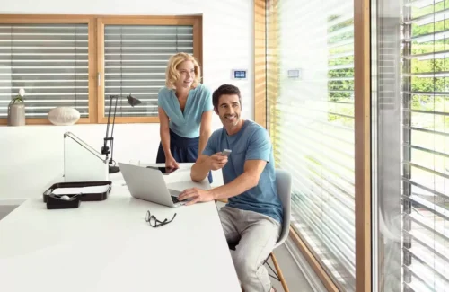 Ein Mann sitzt am Tisch und steuert seinen Rollladen per Fernbedienung